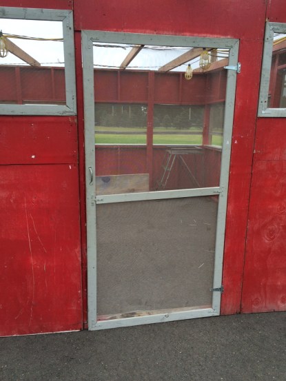 Flimsy screen door on a shabby red wall