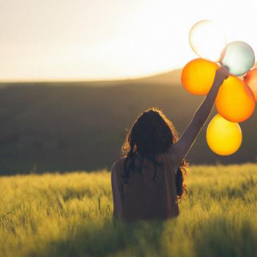 Girl holding up Balloons gold yellow Cata Unsplash
