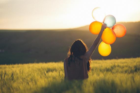 Girl holding up Balloons gold yellow Cata Unsplash